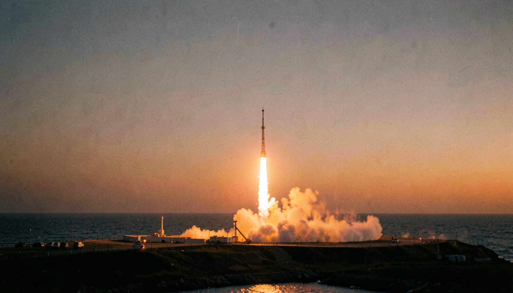 A small rocket lifting off from a coastal launch pad, its exhaust plume bright against a twilight sky